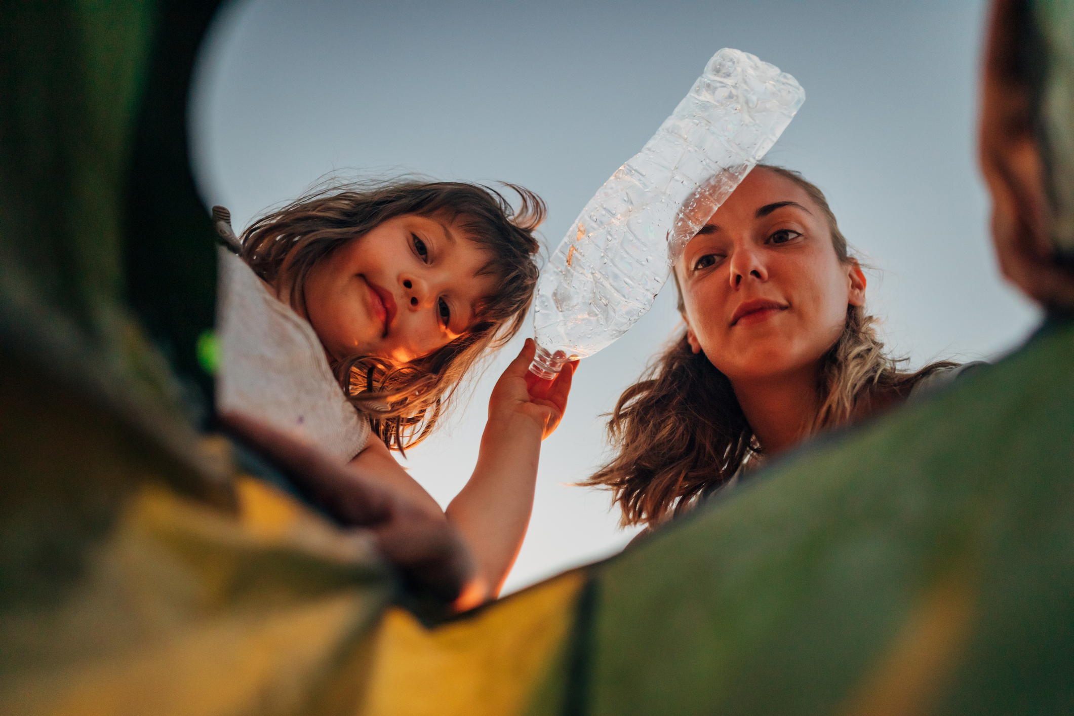 A woman and a little girl throw plastic bottles into a plastic bag